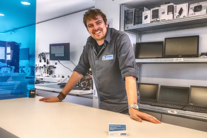 Technician leaning at counter of Mister Genius, Waterloo
